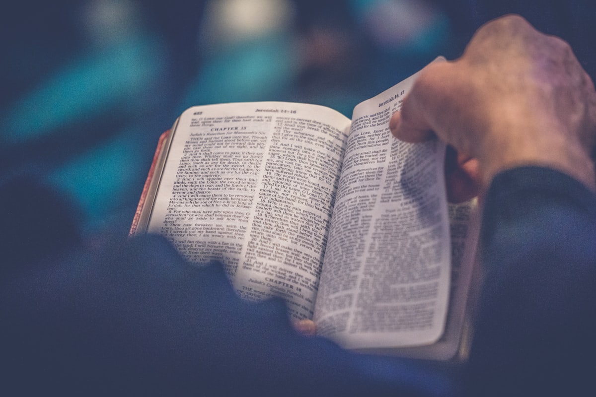 Main tenant délicatement une page de Bible ouverte